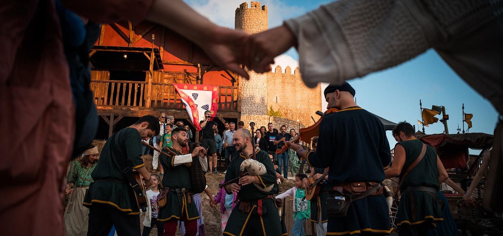 A group of people in medieval costumes are holding hands in a circle.