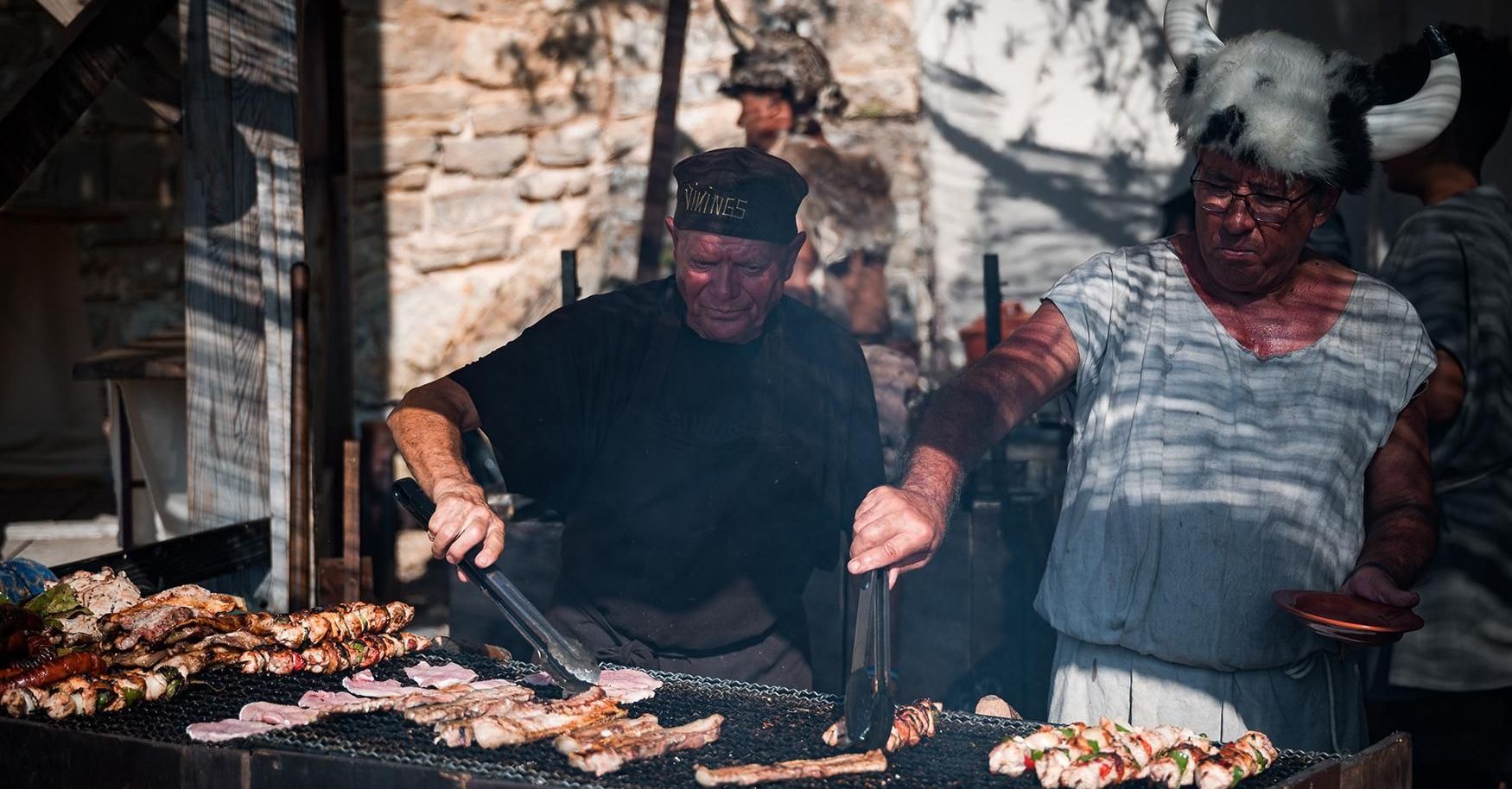 A man and a woman are cooking food on a grill.