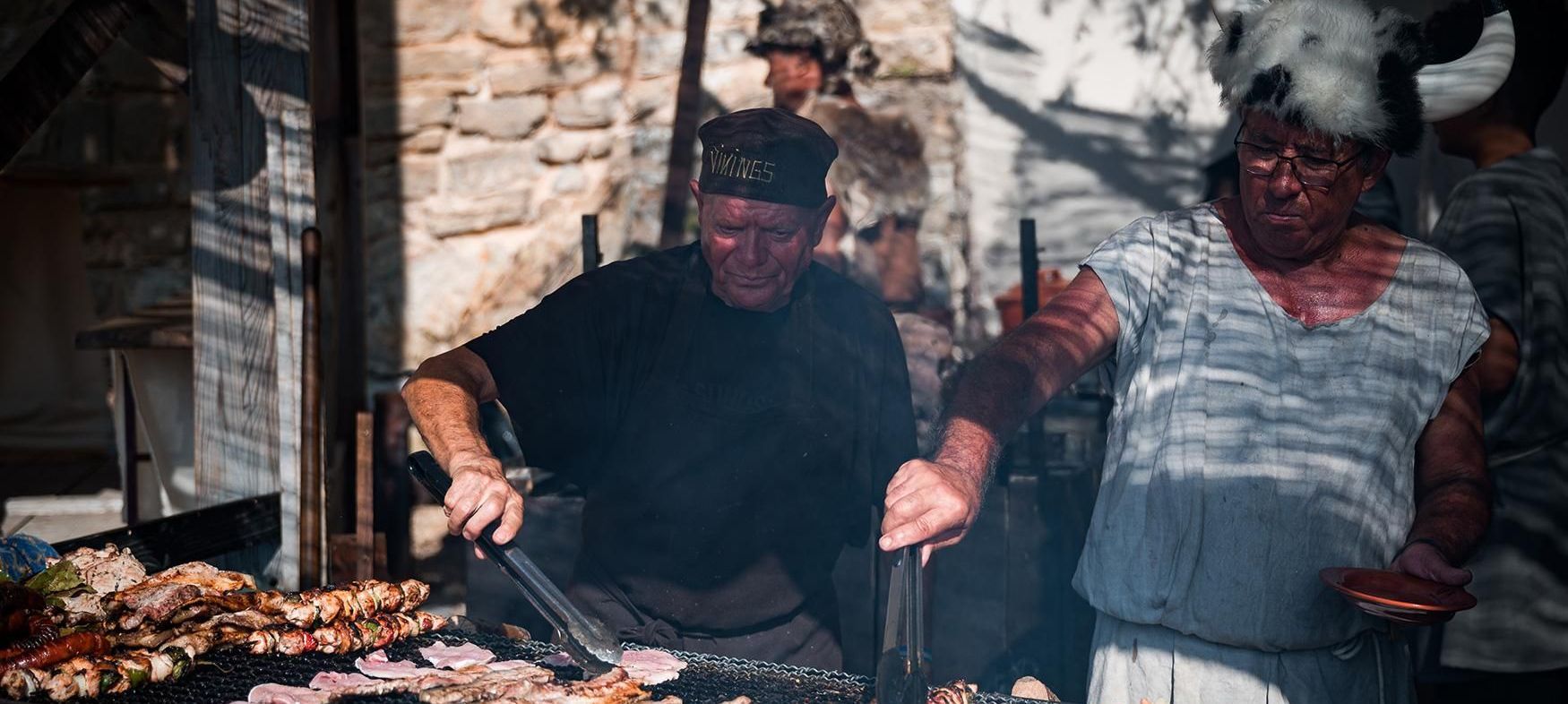 A man and a woman are cooking food on a grill.