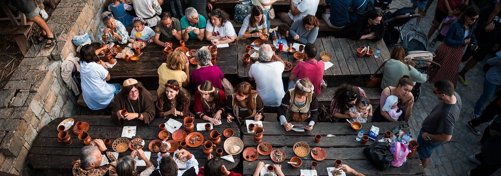 A large group of people are sitting at tables eating food.