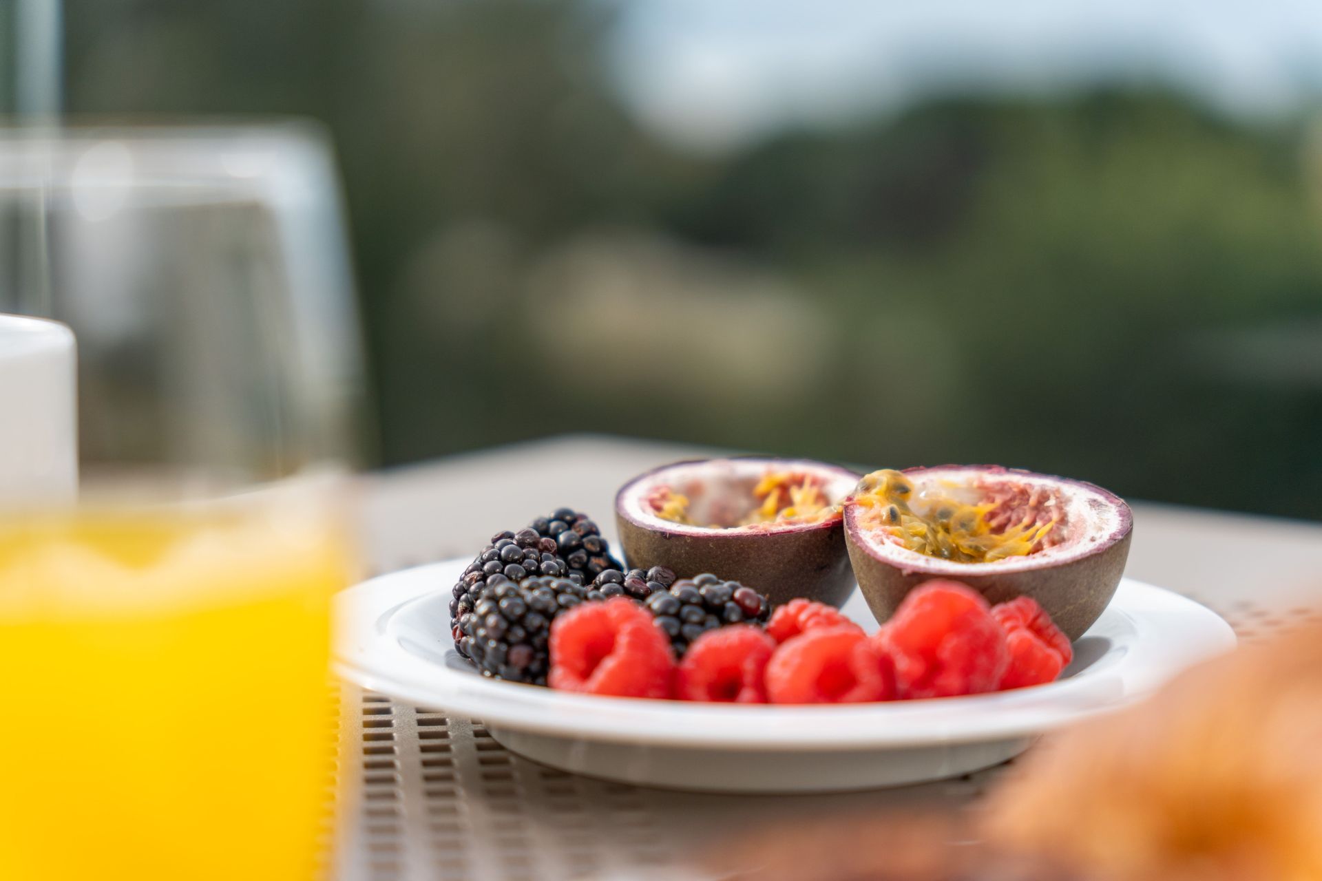 A plate of fruit and a glass of orange juice on a table.