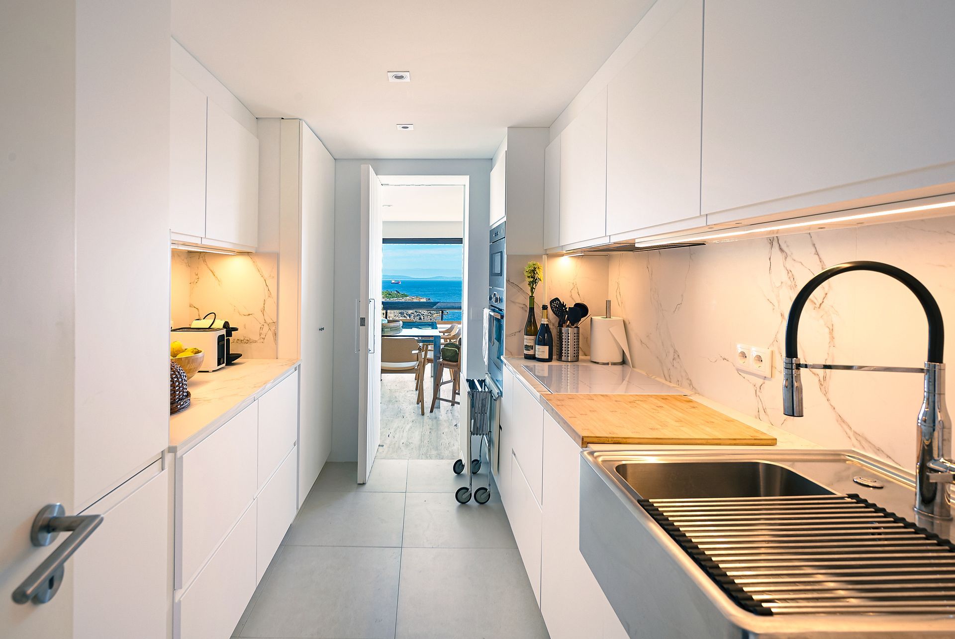 A kitchen with white cabinets and a stainless steel sink