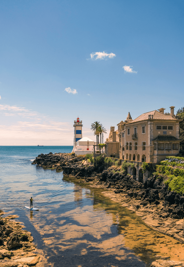 a man on a paddle board in front of a lighthouse Vacation Homes in Cascais