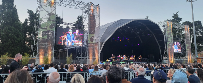 A crowd of people are sitting in front of a large stage at a concert.