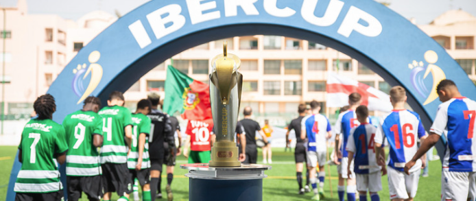 A group of soccer players are walking towards a trophy on a field.