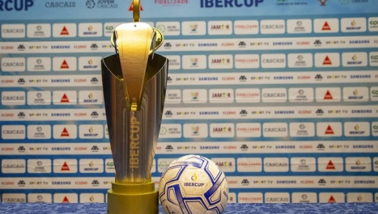 A soccer ball is sitting next to a trophy on a table.