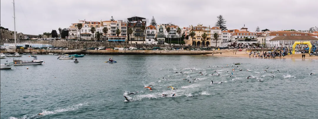 A group of people are swimming in the ocean in front of a city.