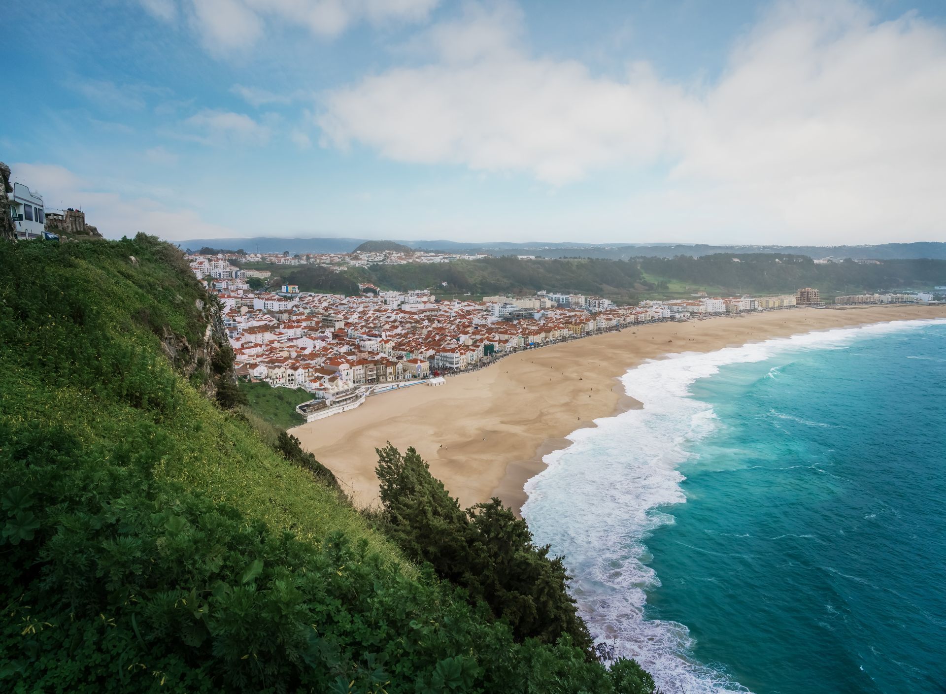 A view of a beach from a cliff overlooking the ocean.