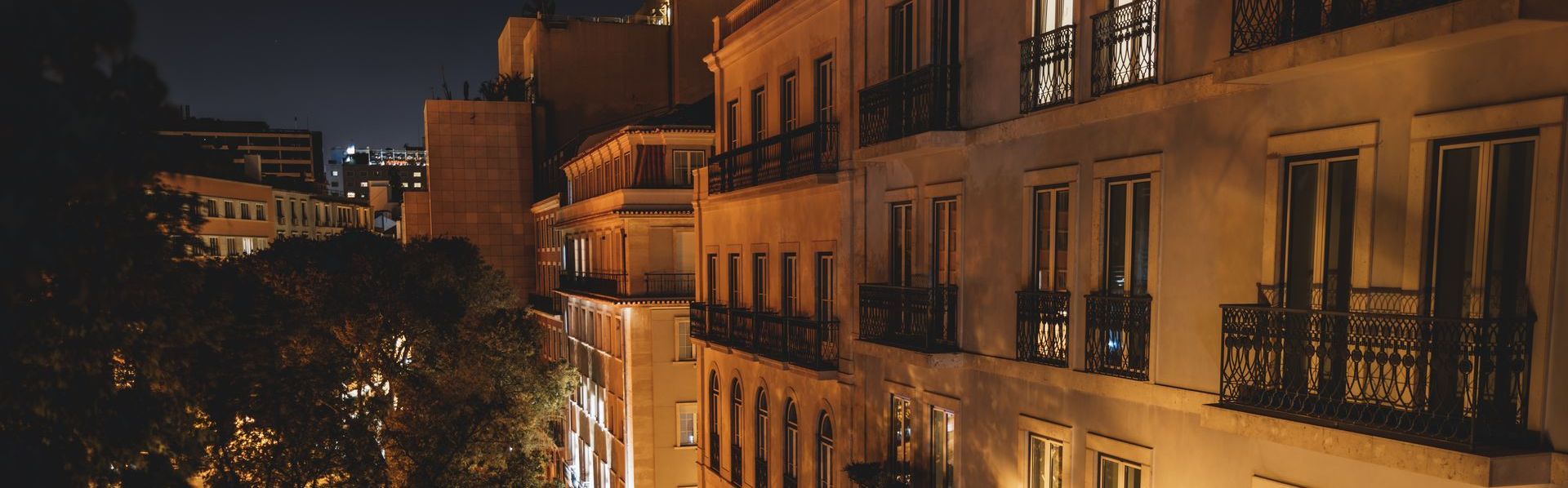 A row of buildings are lit up at night in a city.