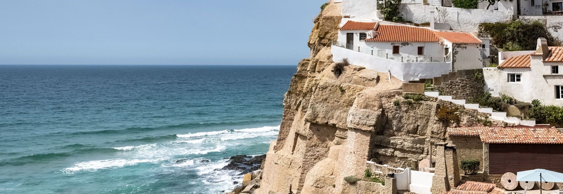 A house on top of a cliff overlooking the ocean.