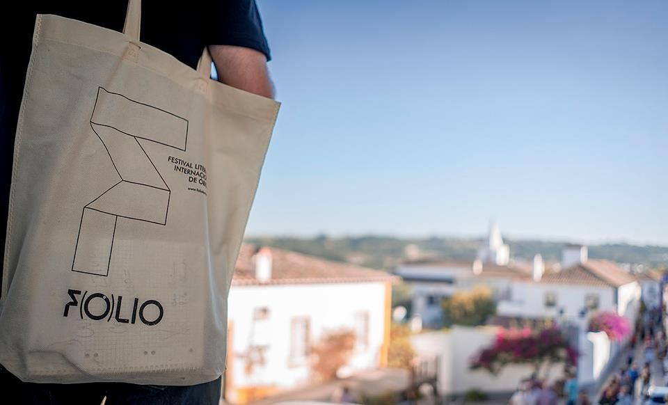 A person is holding a tote bag that says folio on it