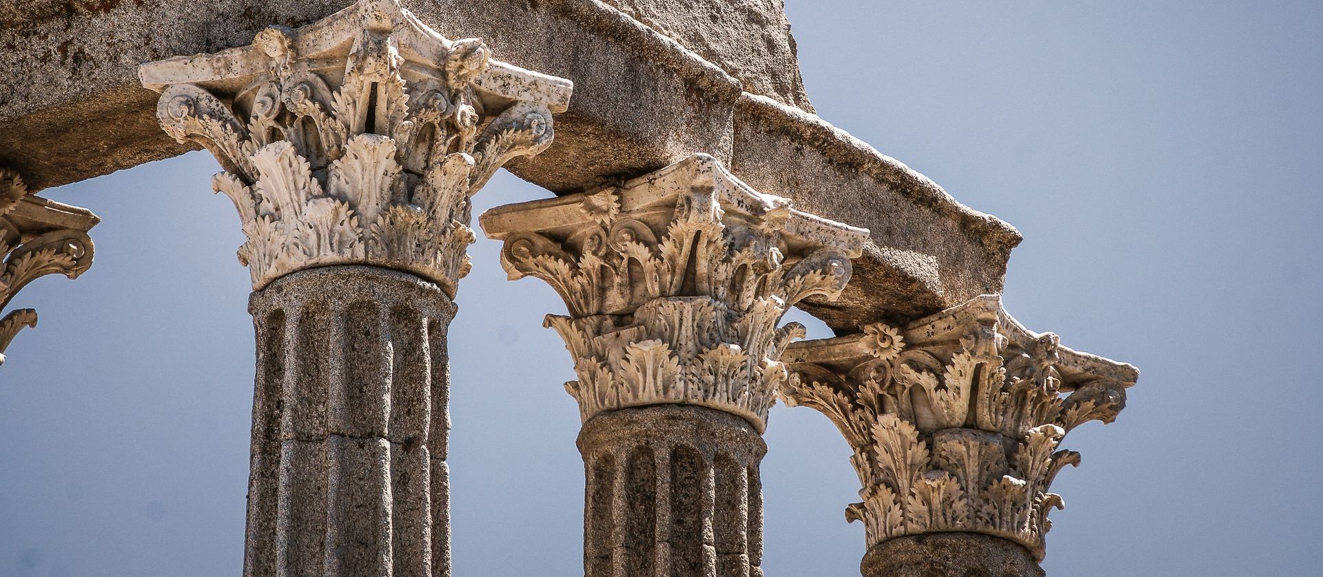 A close up of a row of columns with a blue sky in the background.