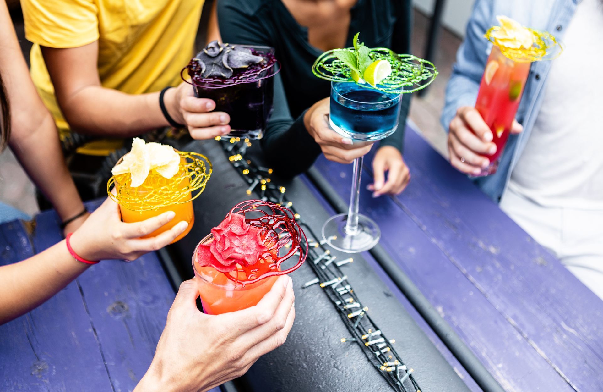 A group of people are sitting at a table holding colorful drinks.