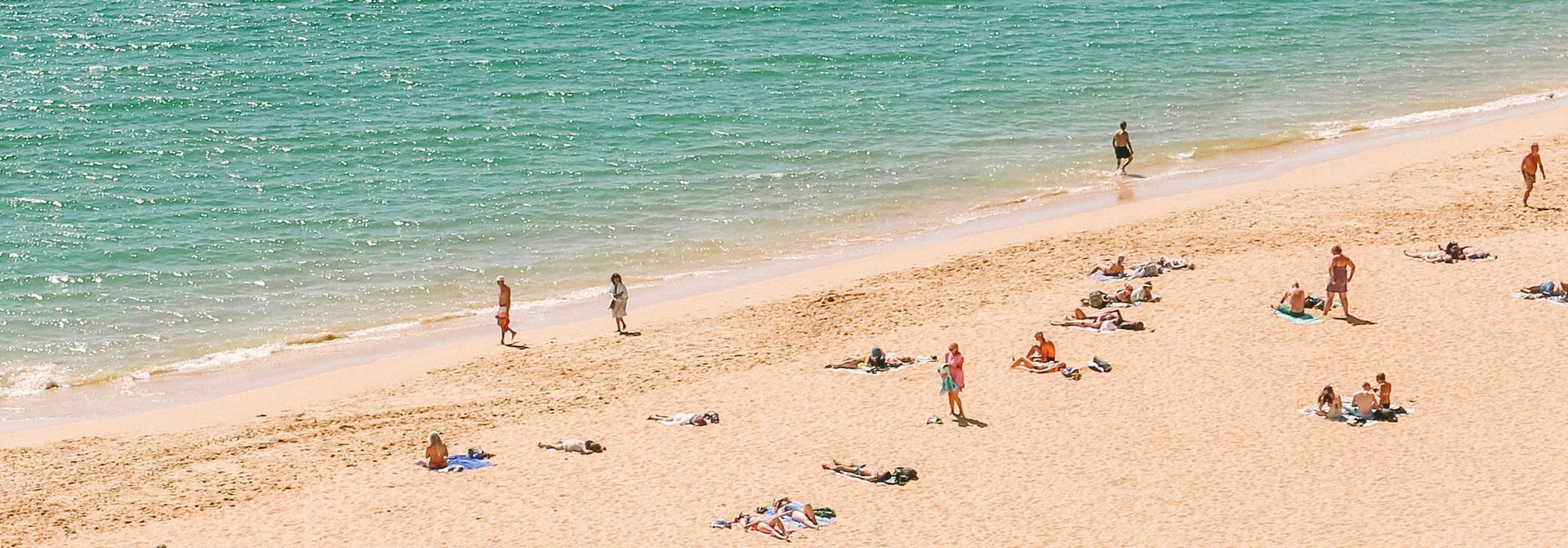 A group of people are sitting on a sandy beach near the ocean.