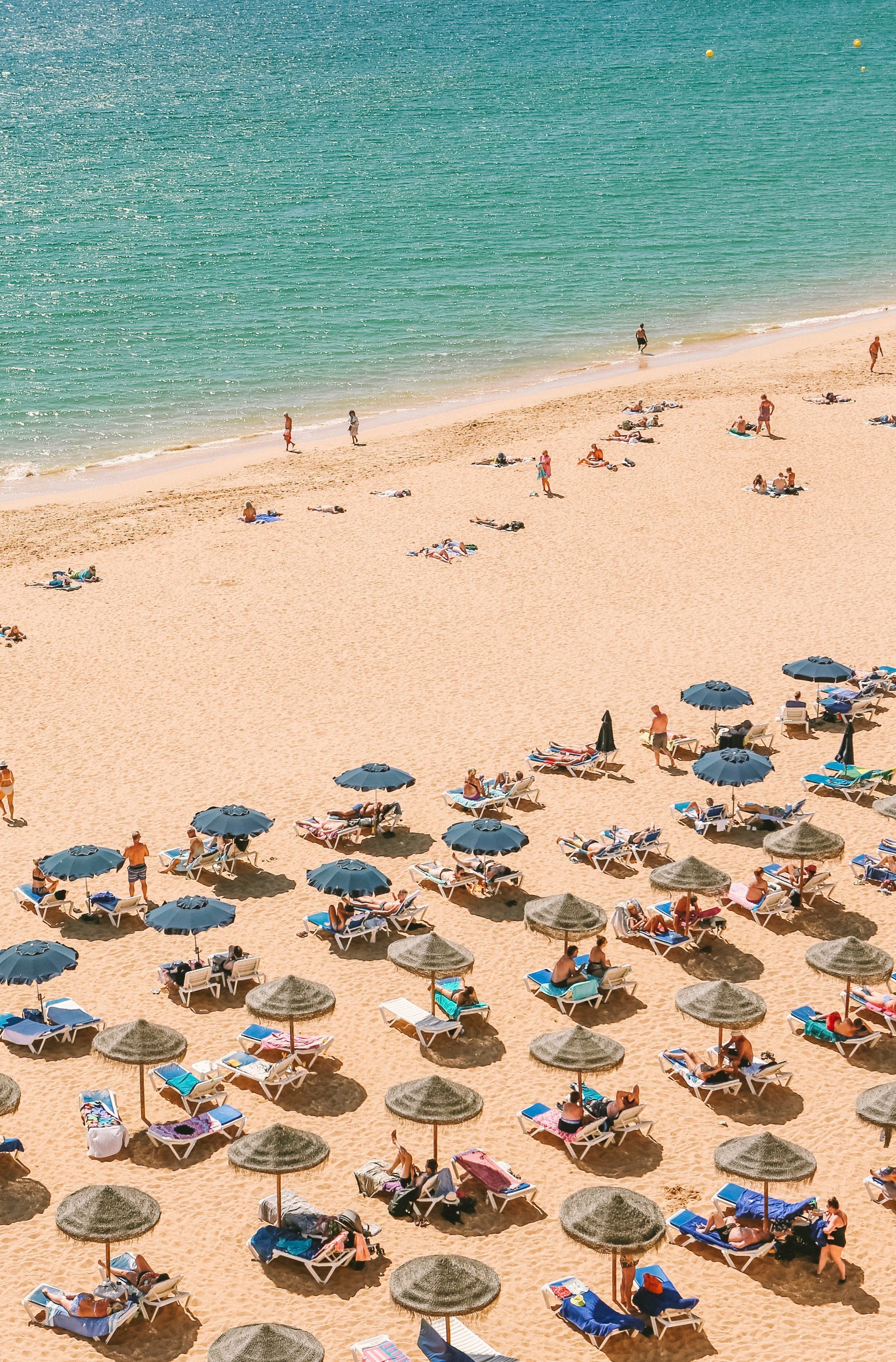 An aerial view of a beach filled with chairs and umbrellas.