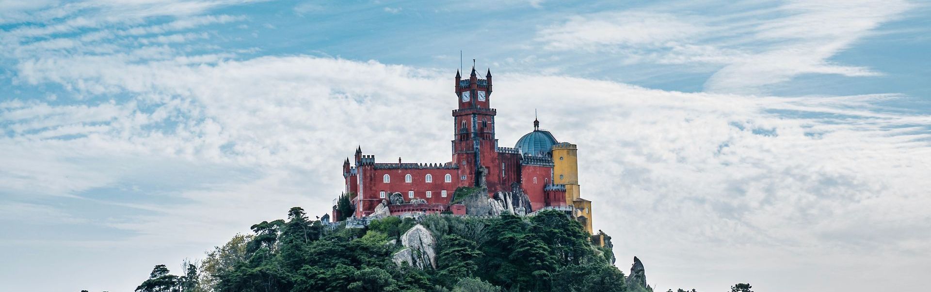 A castle is sitting on top of a hill surrounded by trees.