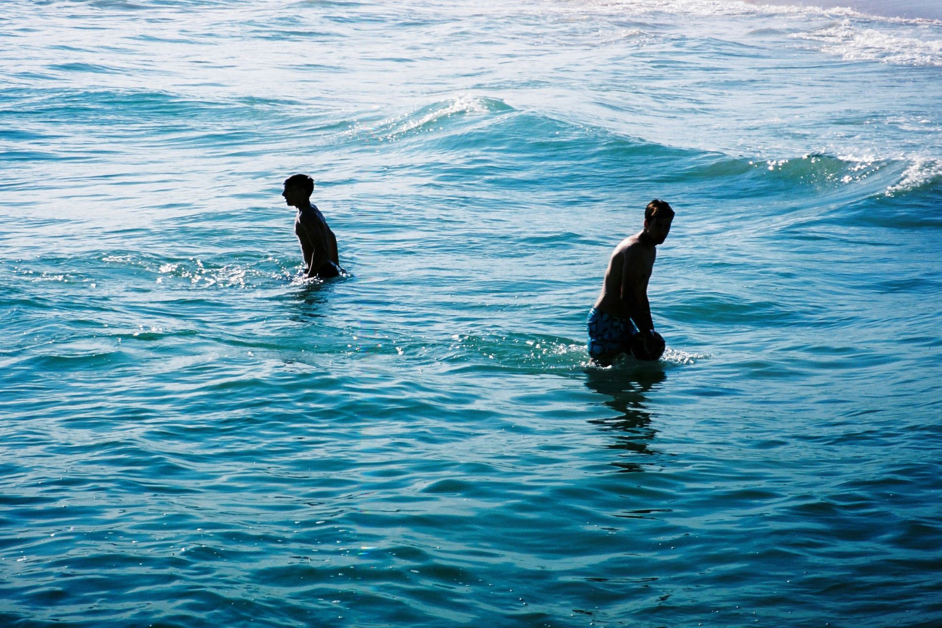 Two people are swimming in the ocean.