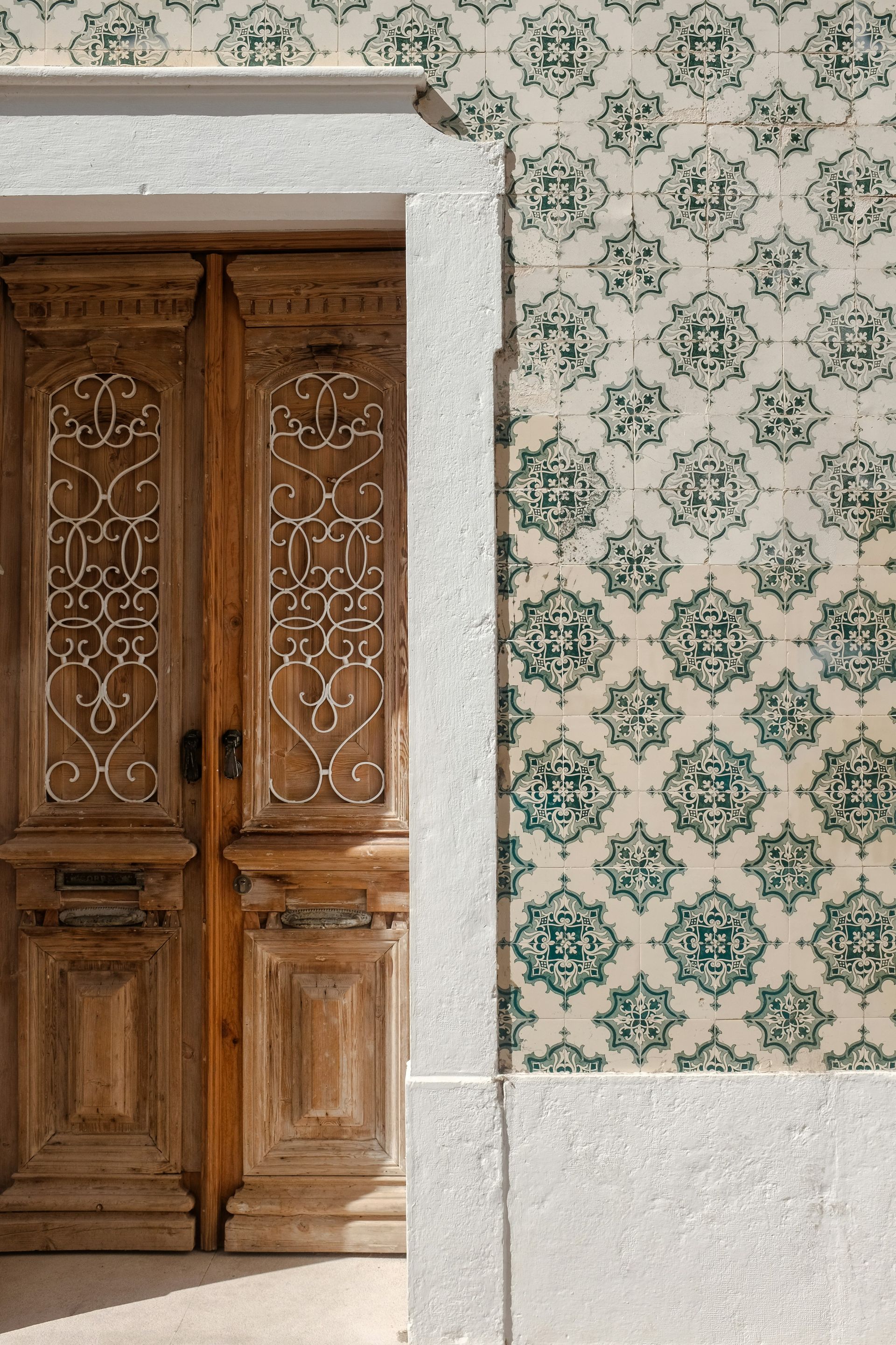 A wooden door is next to a tiled wall.