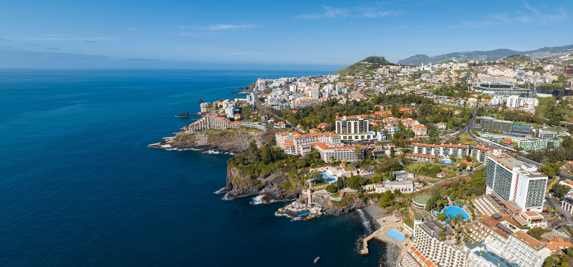 An aerial view of a city on a cliff overlooking the ocean.