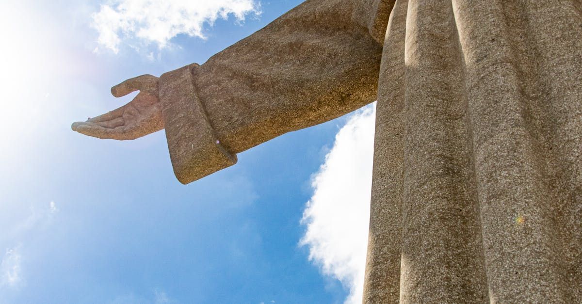 A statue of jesus with his arms outstretched against a blue sky.