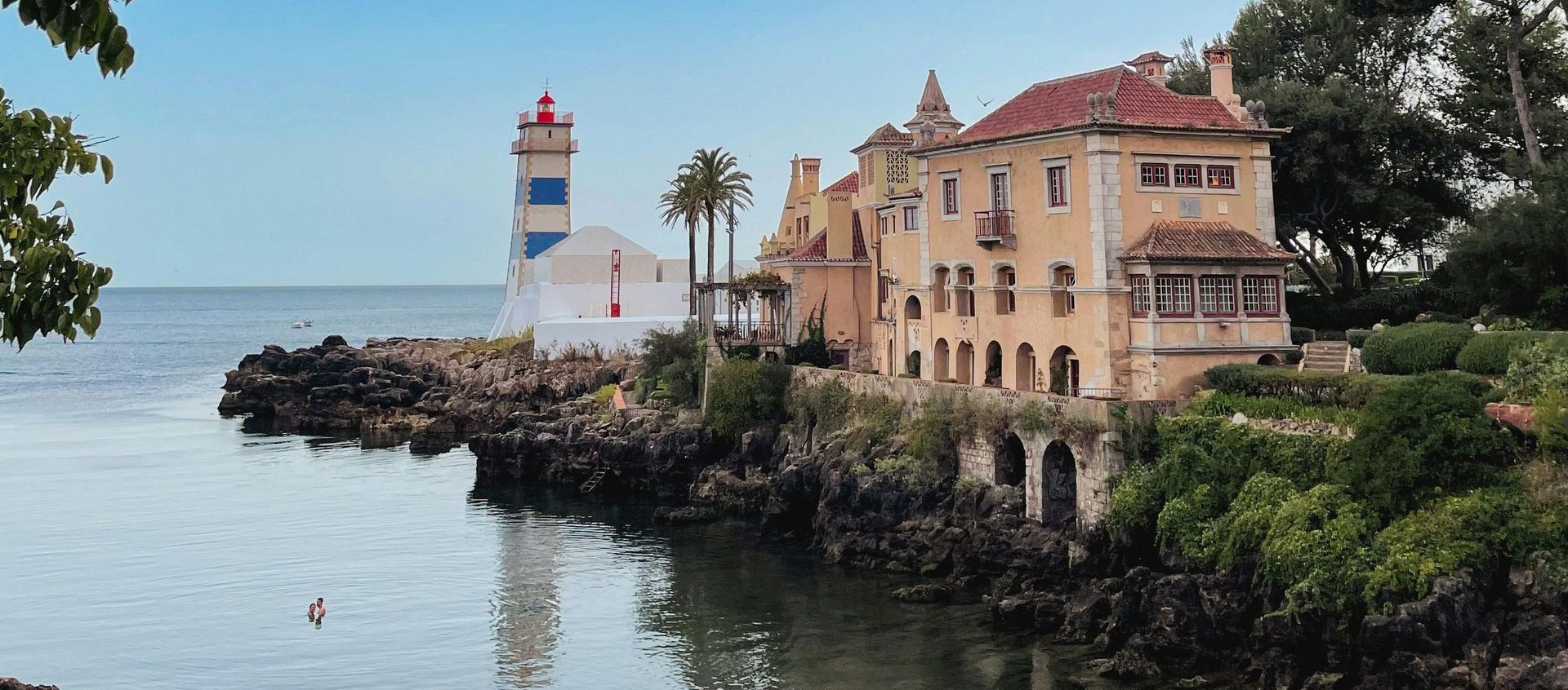 A lighthouse sits on the shore of a body of water