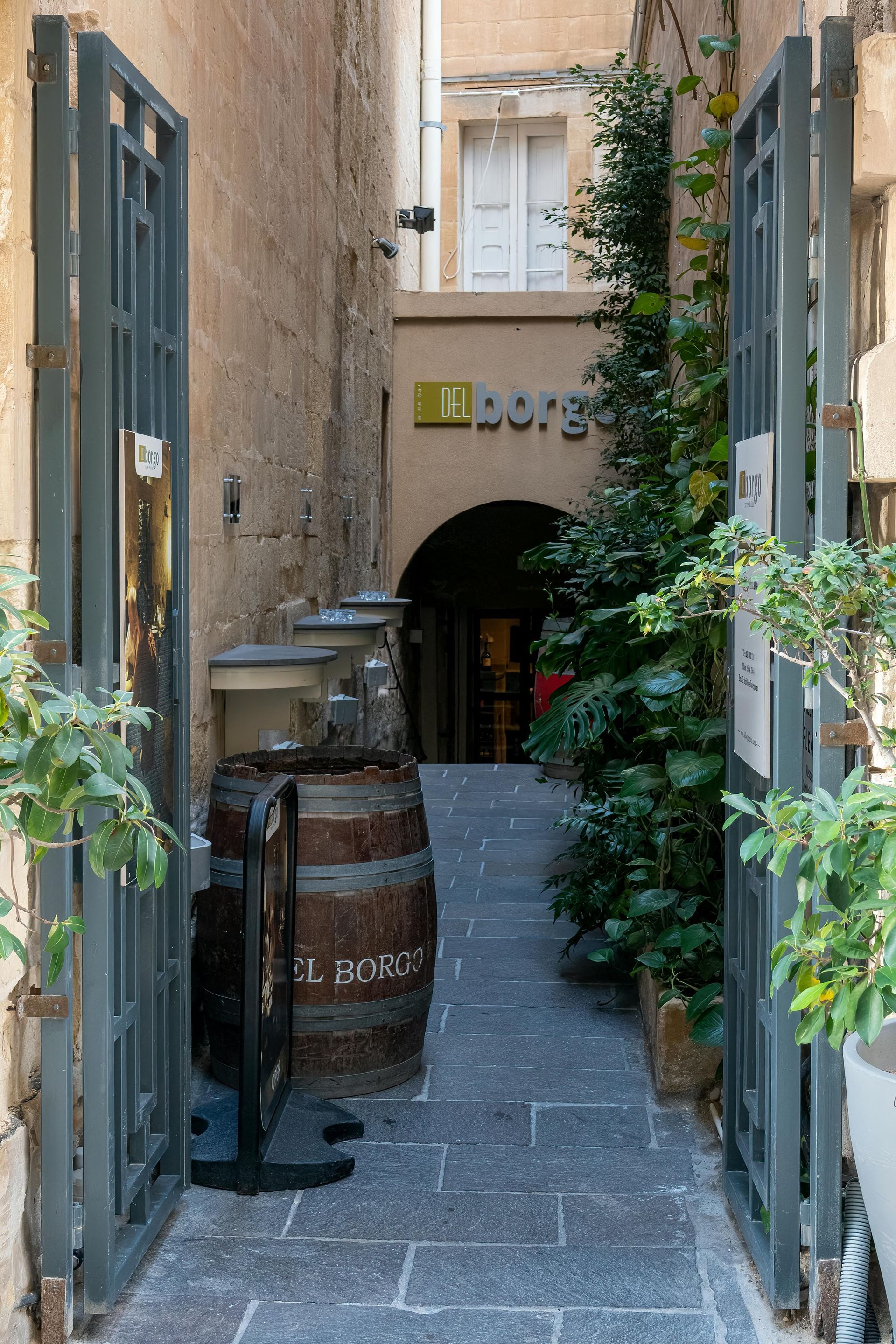 A narrow alleyway leading to a building with a barrel in the middle.