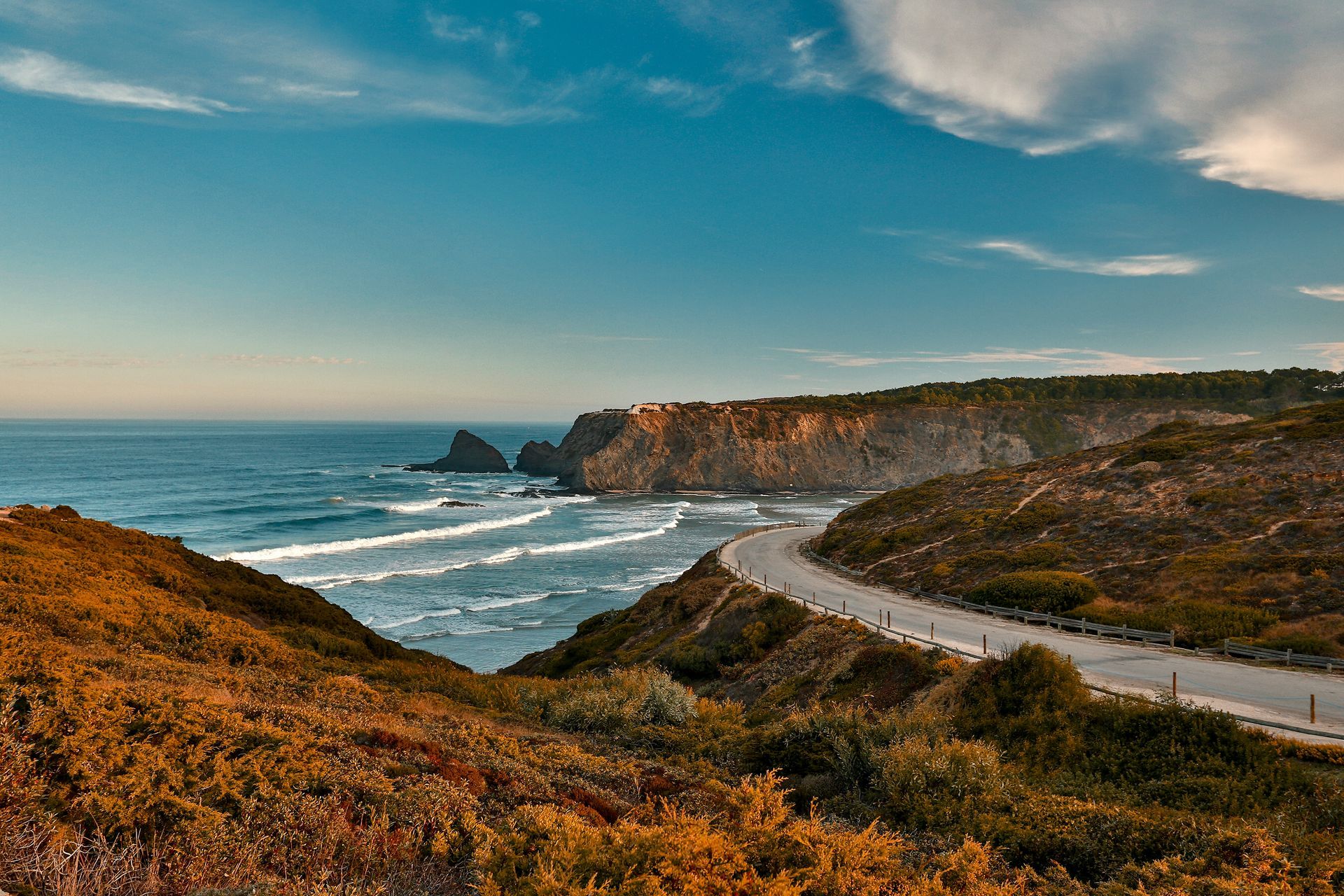 A view of a beach from a cliff overlooking the ocean.