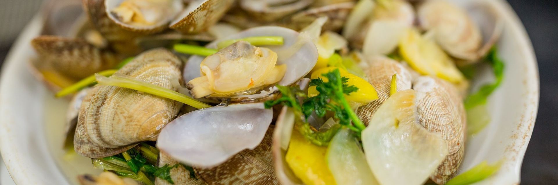 A close up of a plate of food with clams and onions on a table.