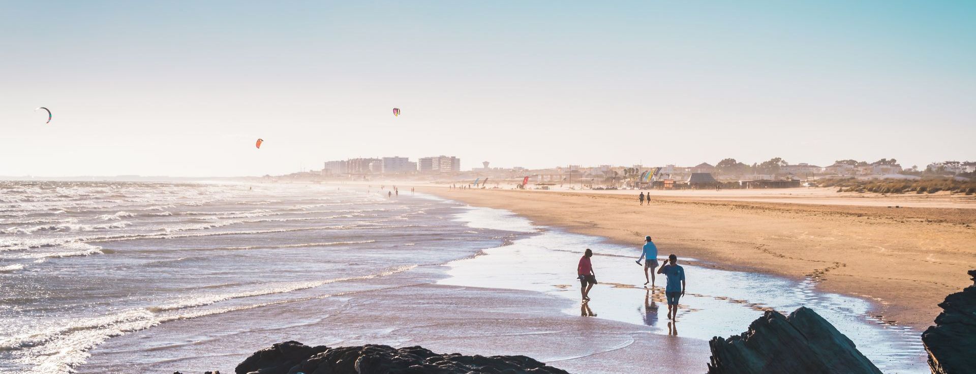 A group of people are walking on a beach near the ocean.