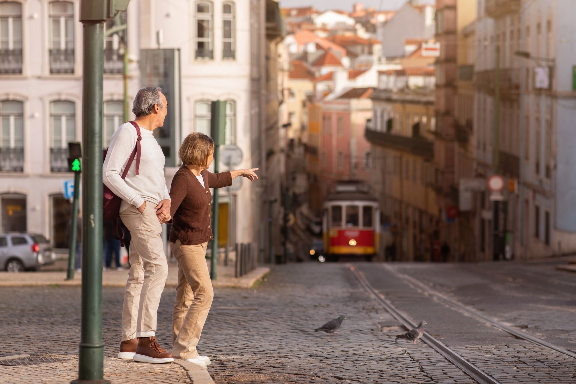 A man and a woman are standing on a sidewalk in front of a trolley.