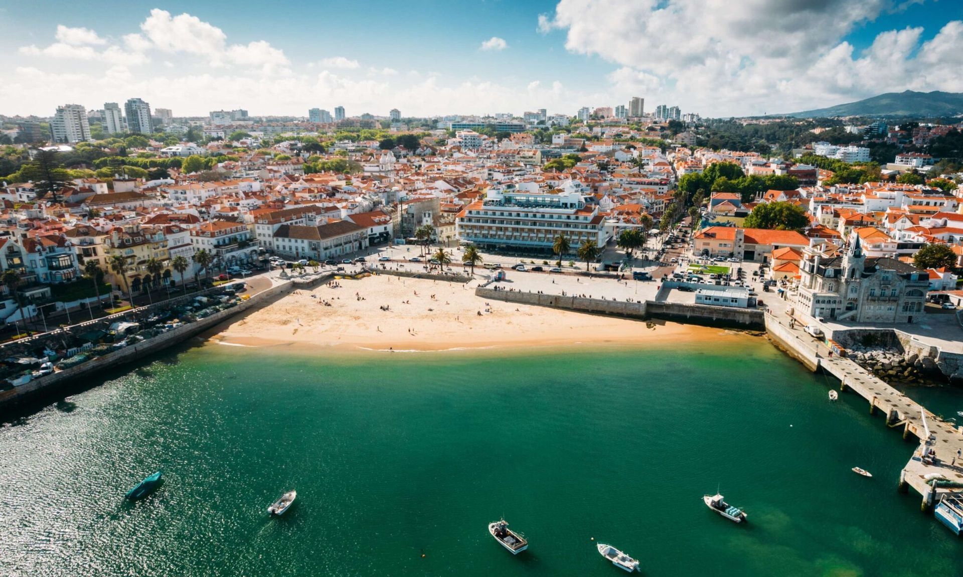 An aerial view of a city with a beach and boats in the water.