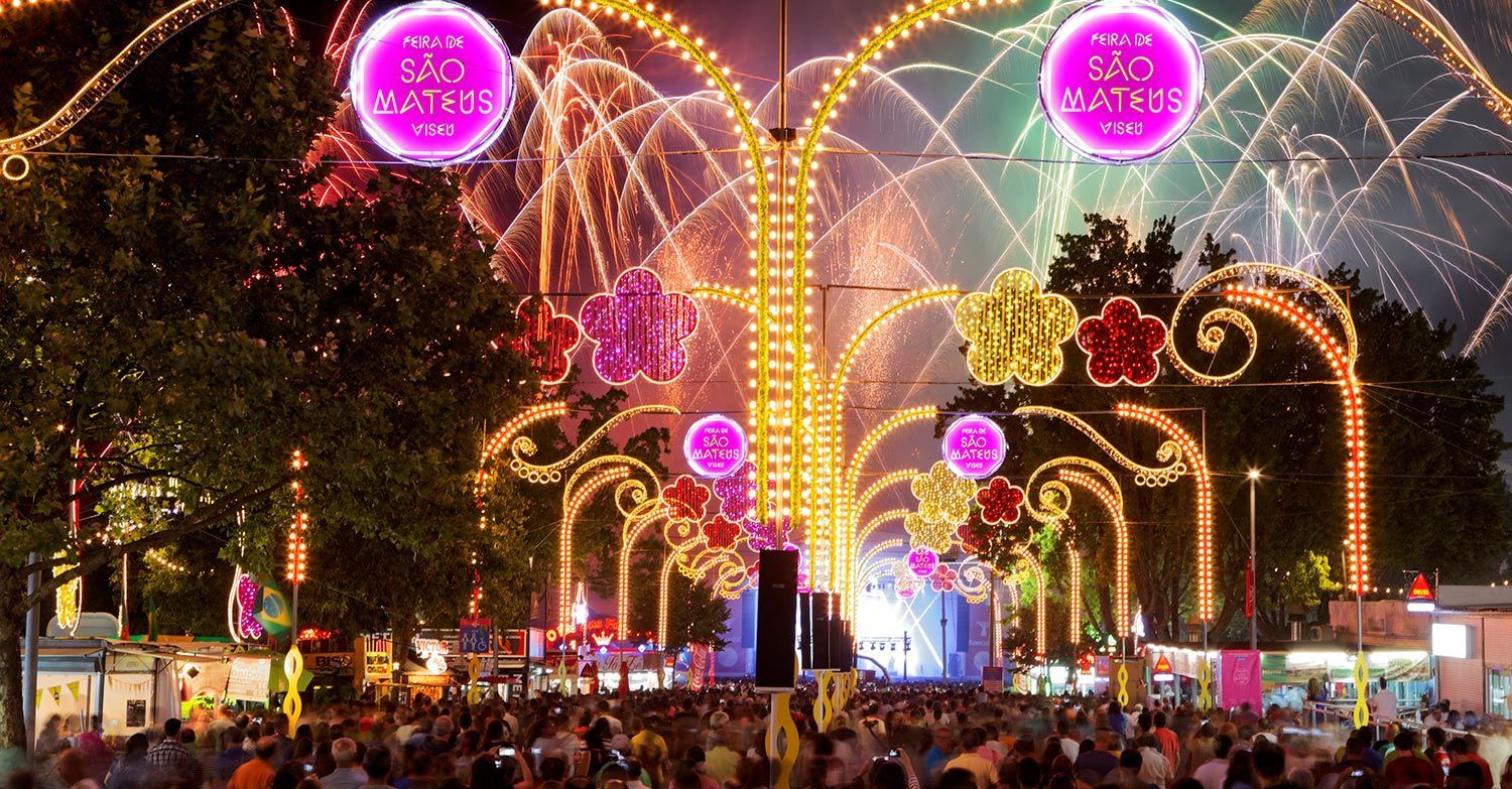 A crowd of people are gathered in front of a display of lights and fireworks.