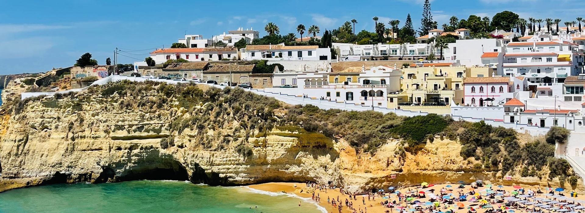 A beach with a lot of people and a small town in the background.