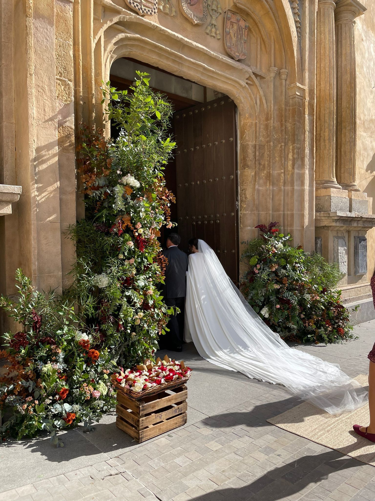 Una novia y un novio entran en una iglesia decorada con flores.