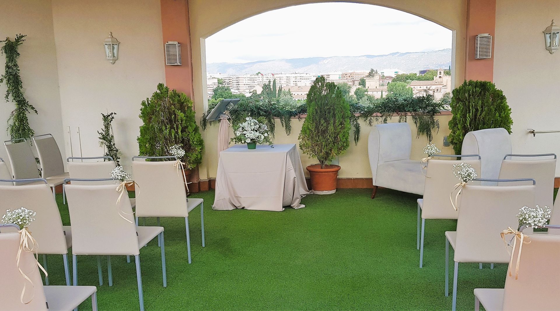 Una fila de sillas están alineadas en un exuberante césped verde frente a una mesa.