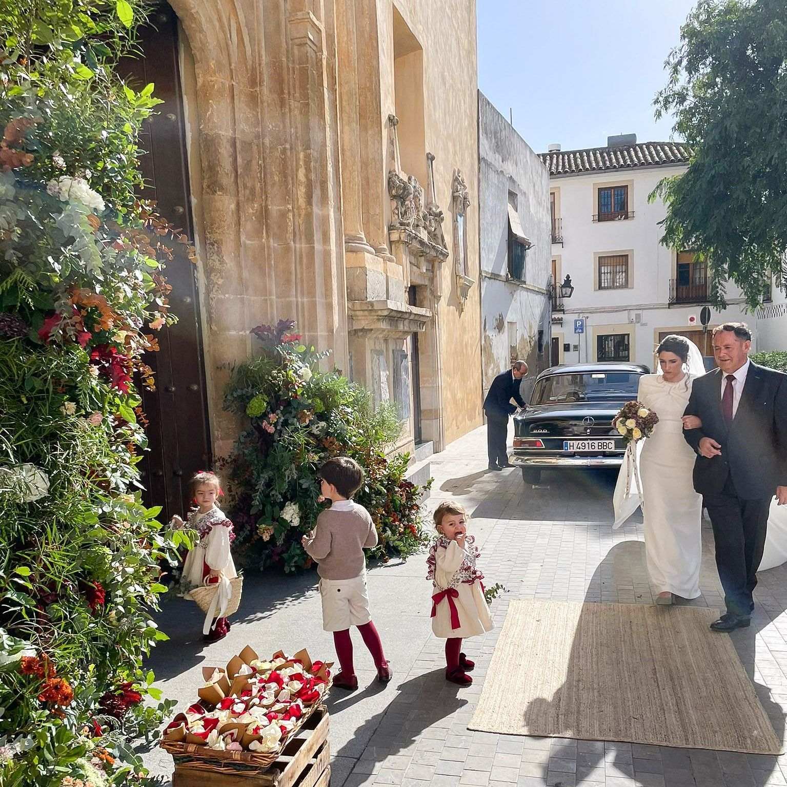 Una novia y un novio caminan por una calle con sus hijos.