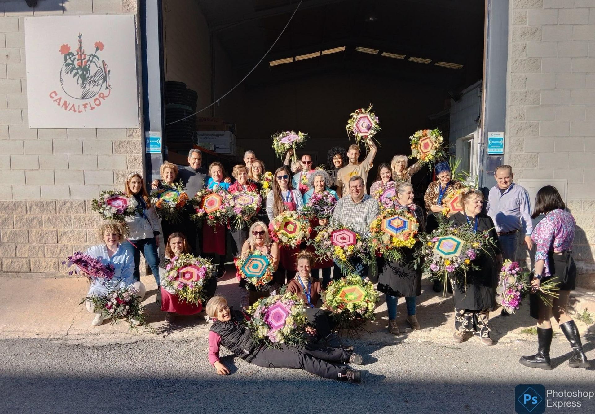 Un grupo de personas paradas frente a un edificio sosteniendo flores.
