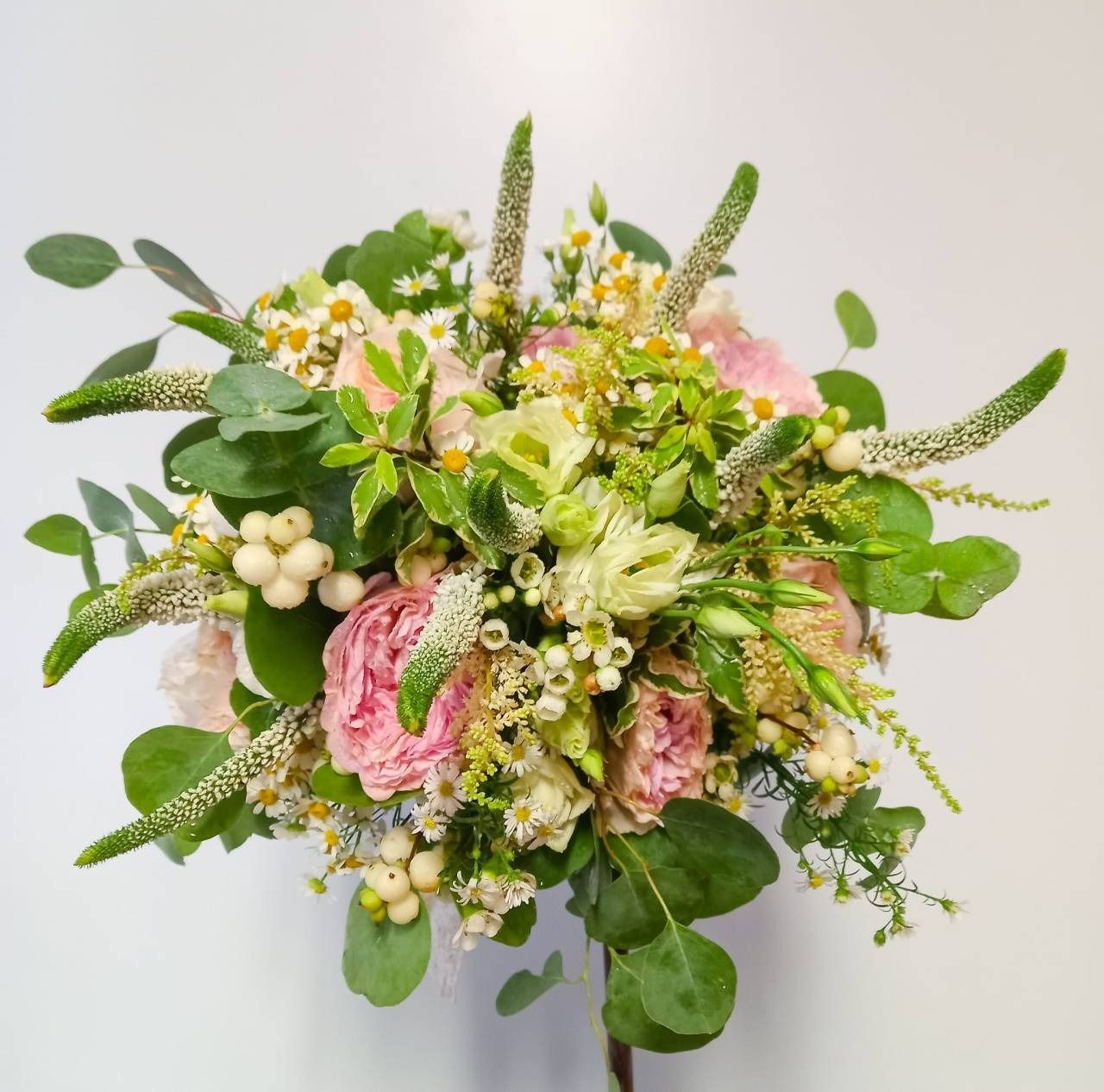Un ramo de flores rosas y blancas con hojas verdes.