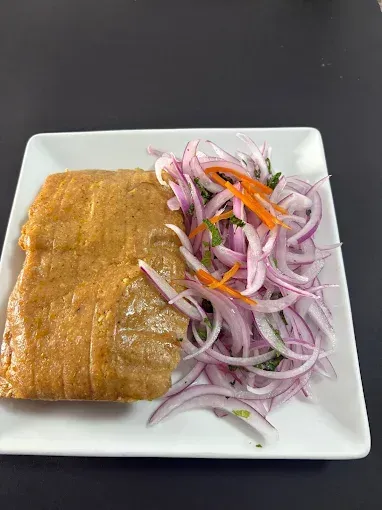 Plato de comida: gran pastel dorado junto a ensalada de cebolla roja encurtida con guarnición de zanahoria.