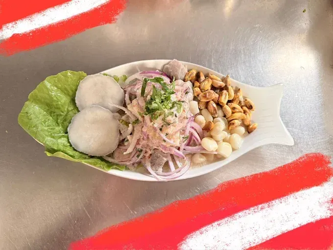Ceviche, plato peruano, plato en forma de pescado, blanco, cebolla roja, maíz, maní, camote cocido, lechuga.