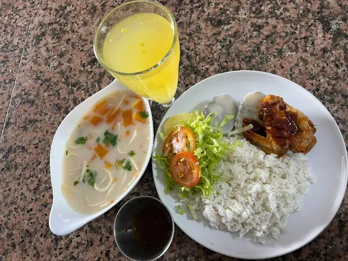 Comida: sopa, arroz, pollo, ensalada y jugo. Sobre una superficie marmolada.