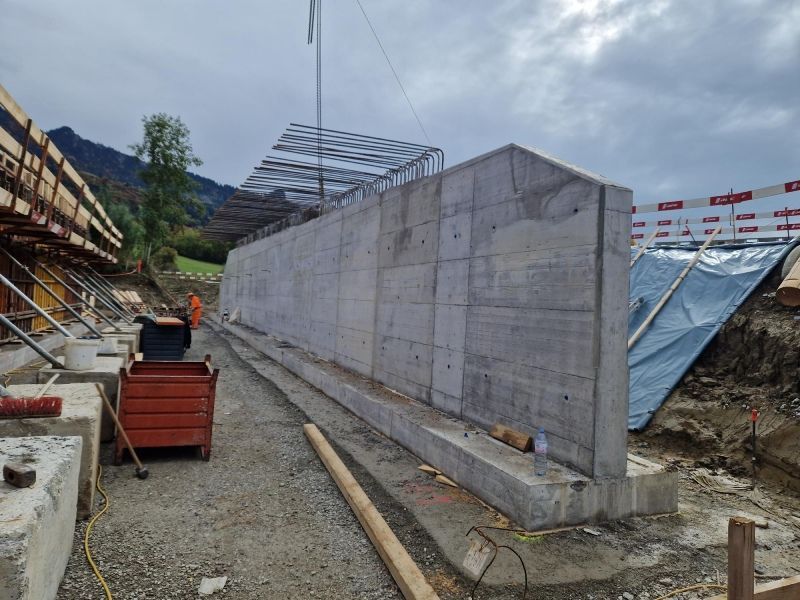 Ein Bauarbeiter schaut durch ein Teleskop auf eine Baustelle.