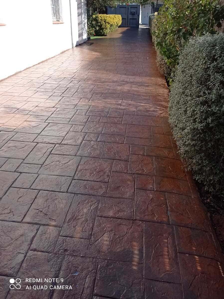 Entrada de hormigón estampado de color marrón con patrones cuadrados y rectangulares.