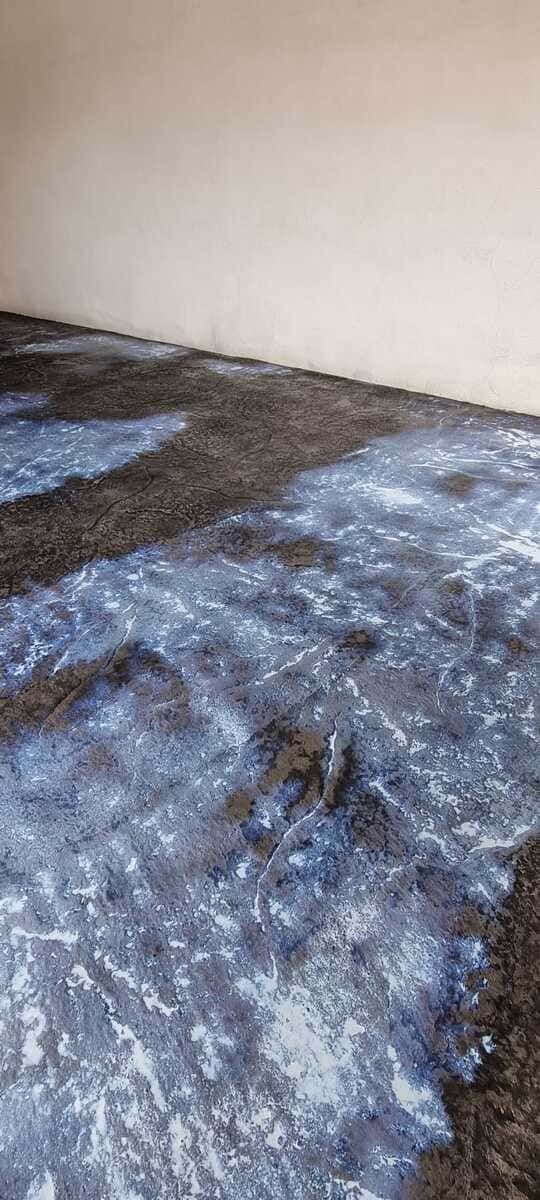 Piso oscuro y manchado contra una pared de color claro.