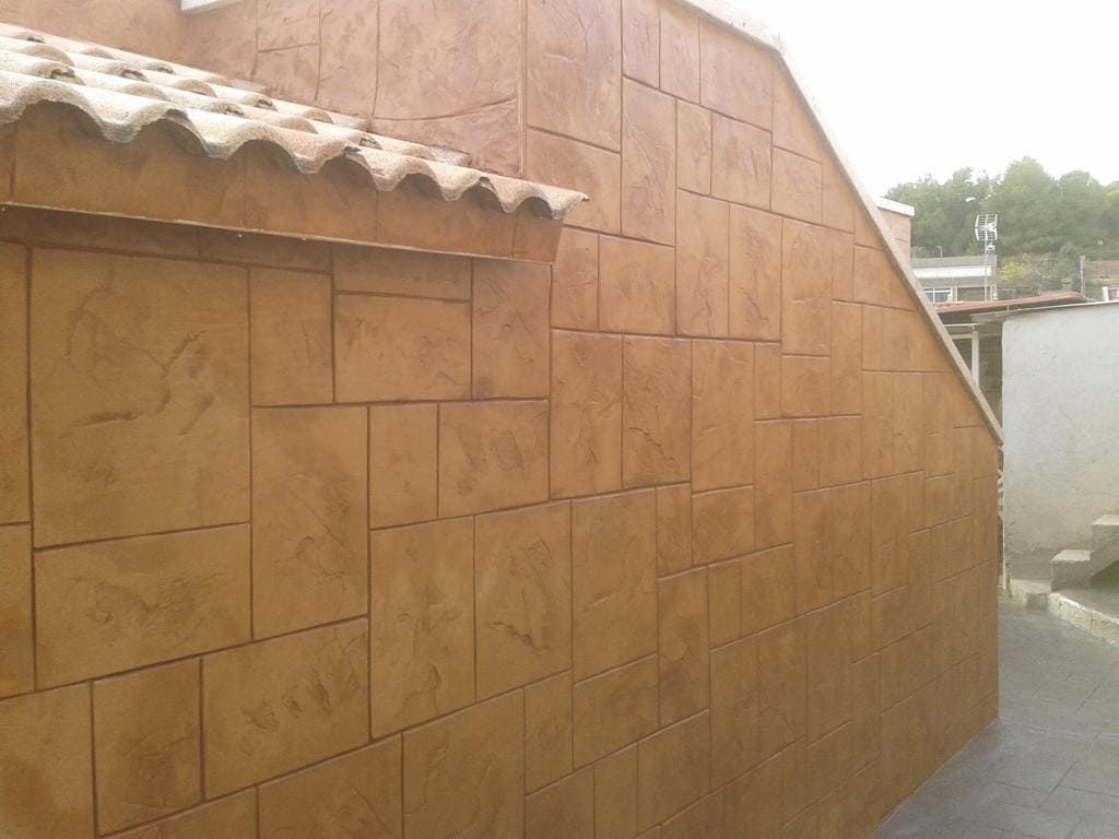 Edificio de color canela con fachada de bloques de piedra falsa, techo en ángulo y bordes de tejas.