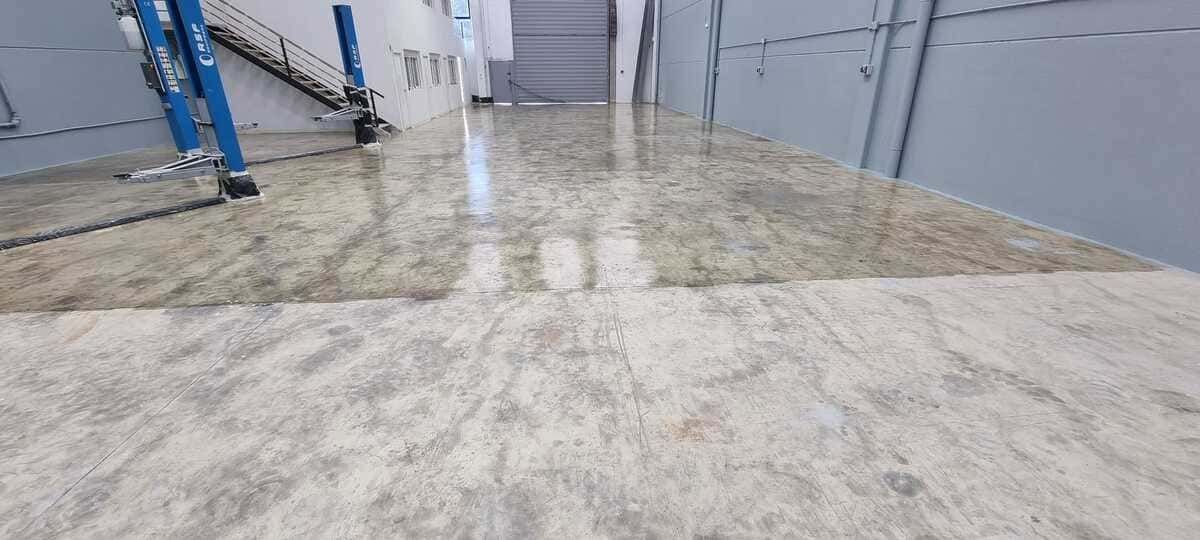 Interior inundado de un gran almacén o nave industrial. El suelo está cubierto de agua.