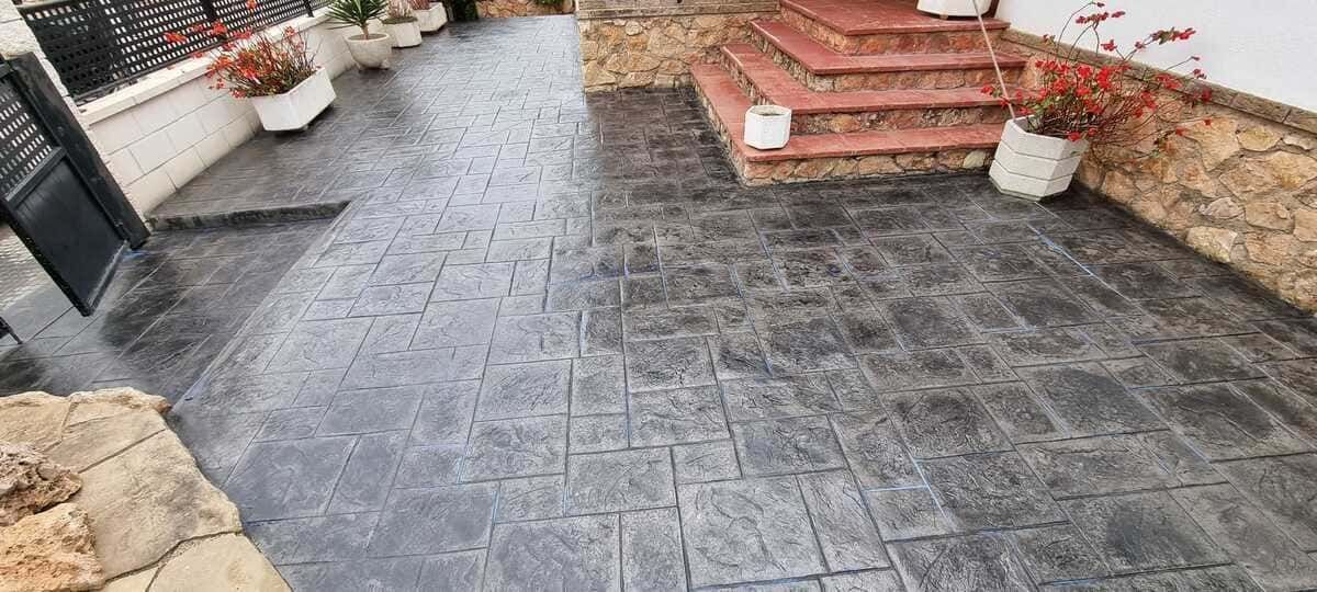 Patio de hormigón estampado que conduce a las escaleras y la entrada de la casa.