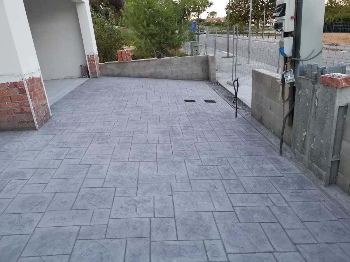 Patio de concreto estampado gris con soportes de construcción y cuadro eléctrico.