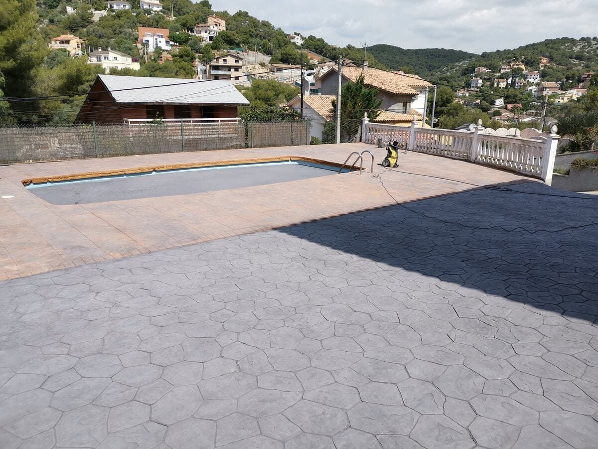Patio junto a la piscina con piscina en primer plano; casas en la ladera en el fondo.