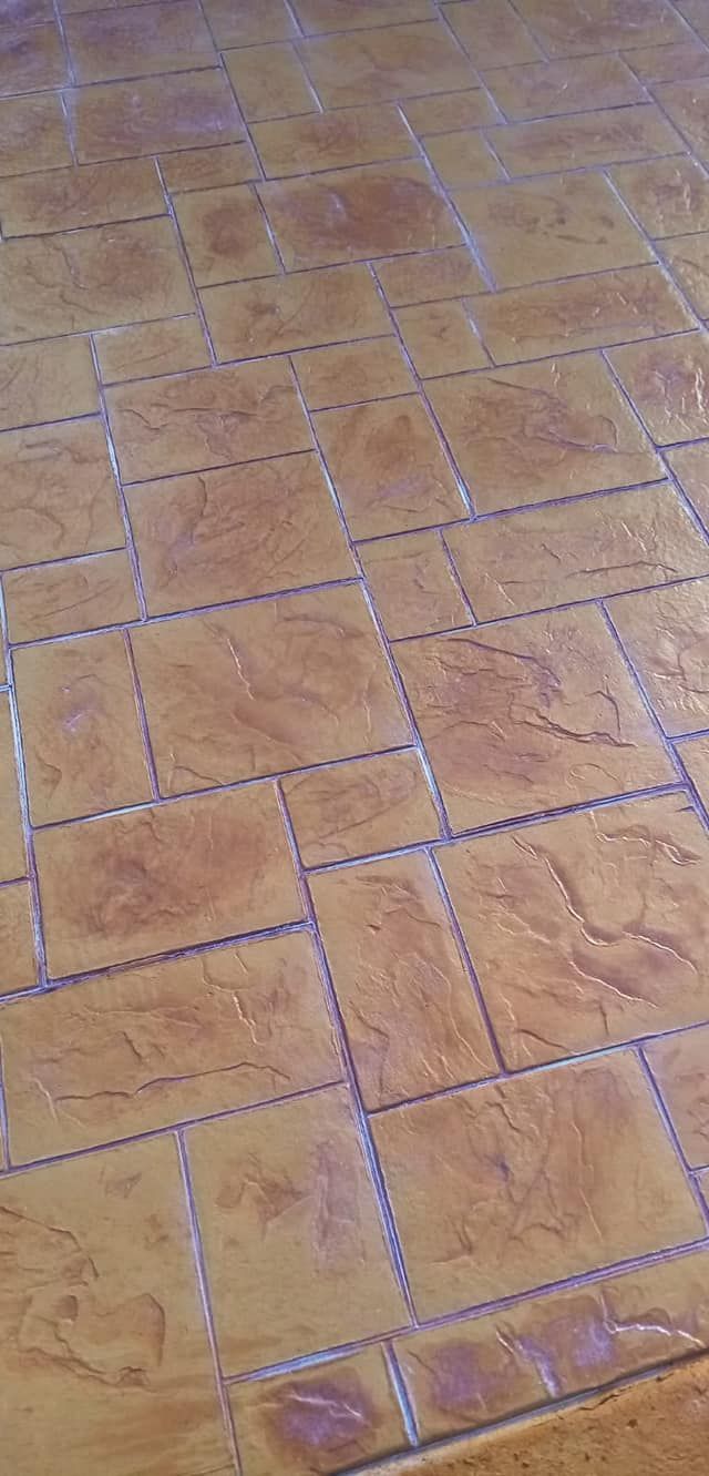 Superficie de hormigón gris recién vertido en un entorno exterior, con edificios al fondo.